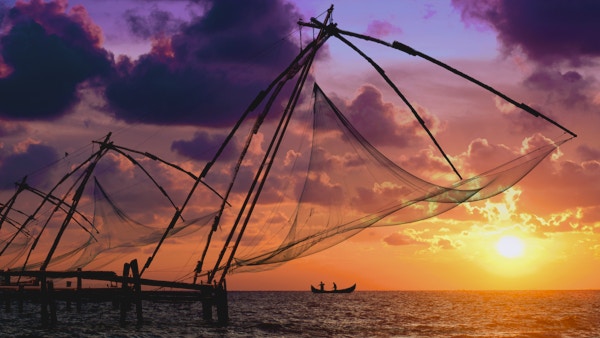 Vakker solnedgang over kinesiske fiskegarn og en båt i Kochi, Kerala, India