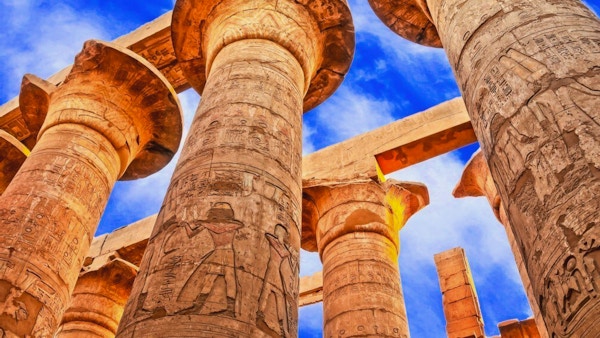 Egyptiske søyker med hieroglyfer fotografert nedenfra mot en blå himmel.