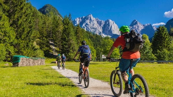 En gruppe terrengsyklister sykler mot fjellkjeden i de Julianske Alpene i nærheten av landsbyen Kranjska Gora. Området er veldig kjent for fotturer og sykling om sommeren og på ski om vinteren.