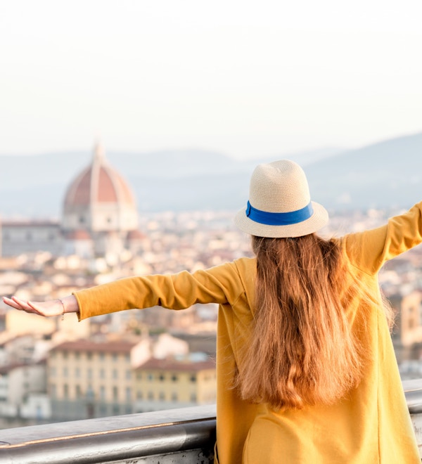 Ung kvinnelig turist nyter utsikten over gamlebyen i Firenze fra Michelangelo-plassen om morgenen i Italia.