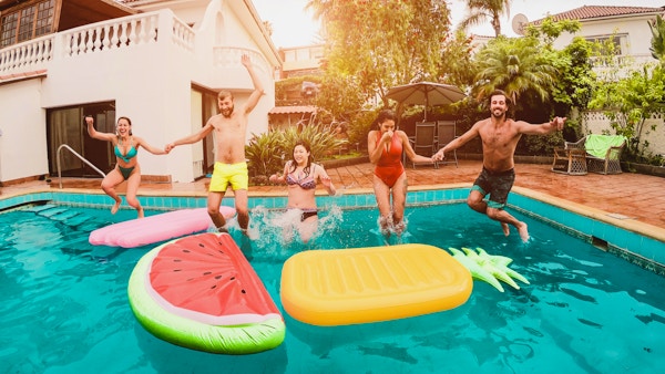 Gruppe glade venner som drikker og hopper i bassenget på solnedgangsfest - Unge, mangfoldige kulturfolk som har det gøy i tropisk ferie - Ferie, ungdom og vennskapskonsept - Hovedfokus på guttefjes