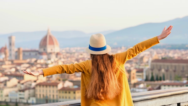 Ung kvinnelig turist nyter utsikten over gamlebyen i Firenze fra Michelangelo-plassen om morgenen i Italia.