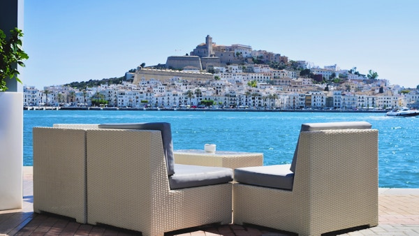 en tom sofa ved Middelhavet, med distriktene Sa Penya og Dalt Vila, gamlebyen i Ibiza by, i bakgrunnen, på Balearene, Spania