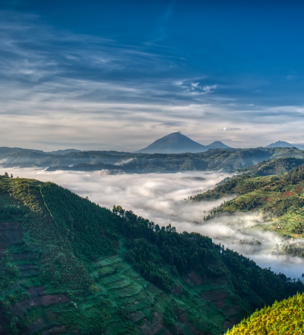 Morgentåke og tåke som strekker seg gjennom dalen i høylandet i Uganda med Mabamba-vulkanen i bakgrunnen