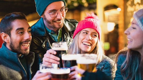 Venner drikker øl på bryggeribaren utendørs om vinteren - Vennskapskonsept med unge mennesker som har det gøy sammen og skåler på happy hour-kampanje - Fokus på jente med rosa hatt - Varmt neonfilter