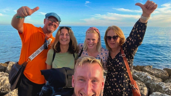 En gruppe mennesker tar selfie ved en strand
