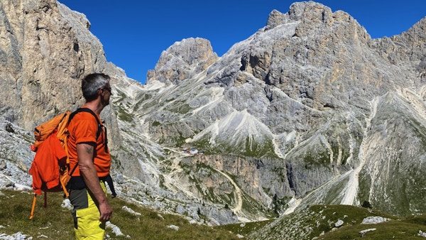 Mann med ryggsekk som ser utover dal og mot høye fjell