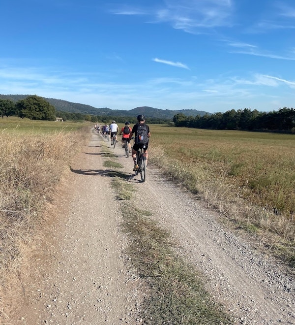 Gruppe syklister sykler langs en grusvei