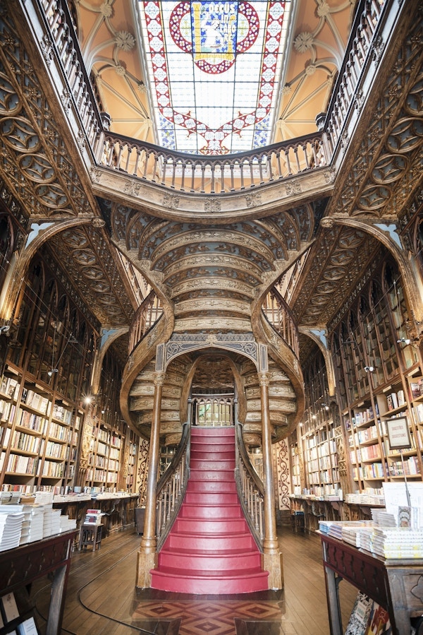 Interiør i bokhandel med utsmykket tak og flott trapp.