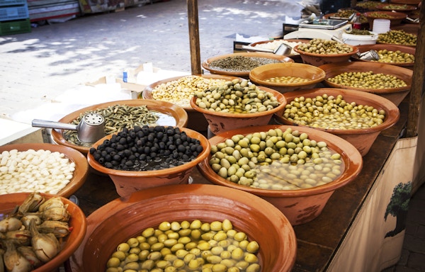Ulike marinerte oliven og lokal mat på gatemarkedet på Mallorca, Spania. Selger og kjøper.