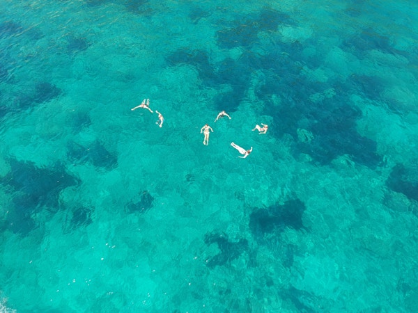 En gruppe mennesker som svømmer i det azurblå havet utenfor Kefalonia