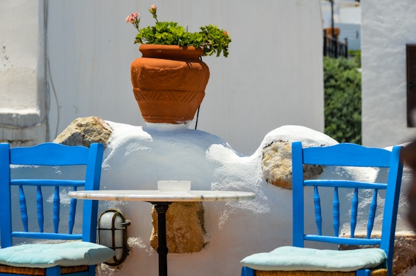 Blå stoler og bord i et smug i Hellas