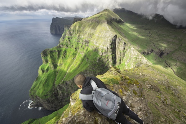 En mann som sitter på toppen av et fjell og ser på den vakre naturen.