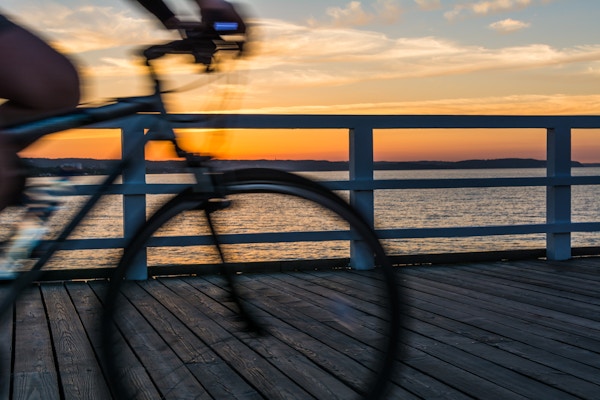 Uklart sykkel på en strandpromenade med solnedgang over Gdansk-bukta.