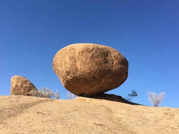 En stor stein ligger plassert såvidt oppå flatmark i et ørkenlandskap