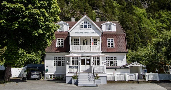 Et hvitt trehus i gammel stil er hovedhuset på Valldal Fjord Lodge