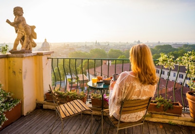 Dame spiser frokost på balkong i Italia med flott utsikt.