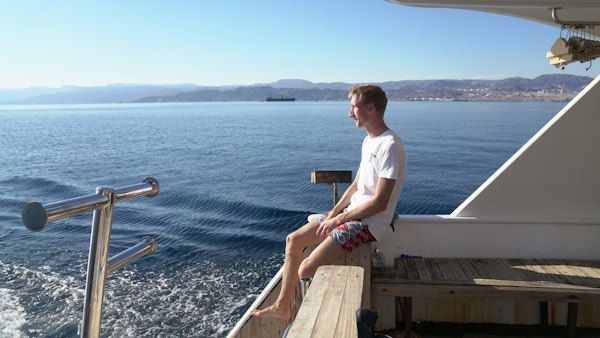 Turleder Carl sitter ved akterenden av båten og ser ut mot havet