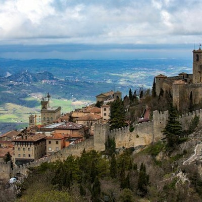 Slott med bymurer på en høyde med utsikt over landskap