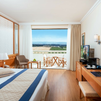 Hotellrom med stor seng, skrivebord og balkong med utsikt