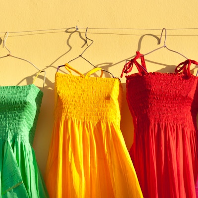 Fargerike meksikanske kjoler vist på kleshengere i en turist-souvenirbutikk i Cozumel, Riviera Maya, i Cancun Mexico. Den fargerike latinermoten er en populær turist-suvenir. Fotografert på Plaza del Sol på øya Cozumel i horisontalt format.
