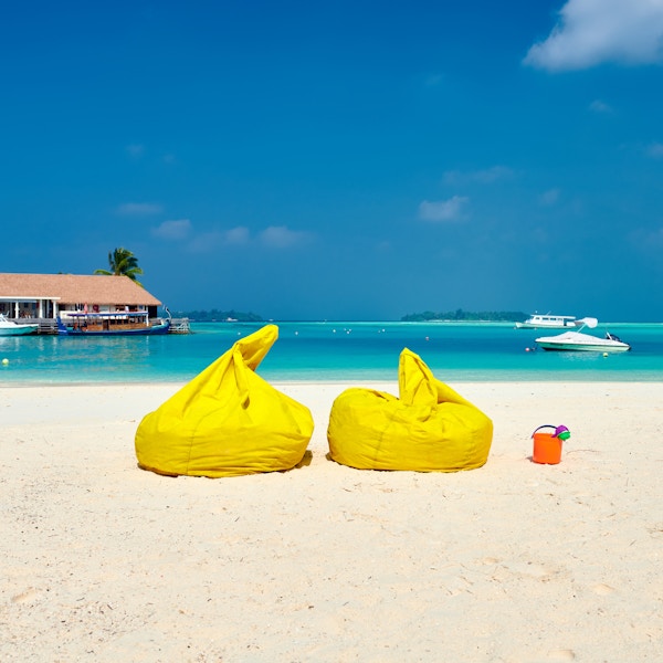 Tropisk strand med gule beanbag-stoler. Sommerferie på Maldivene.