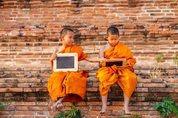 To nybegynnere som leser og studerer hver sin tavle i et gammelt tempel ved solnedgangstid, Ayutthaya-provinsen, Thailand