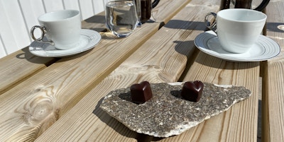 Et steinfat med to sjokoladehjerter med kaffekopper ved siden av