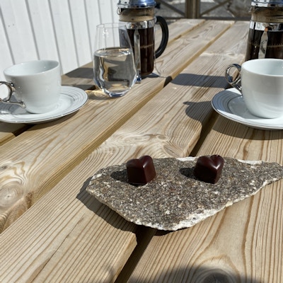 Et steinfat med to sjokoladehjerter med kaffekopper ved siden av