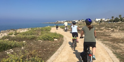 En gruppe mennesker sykler på grussti langs kysten ved Capilungo, Puglia