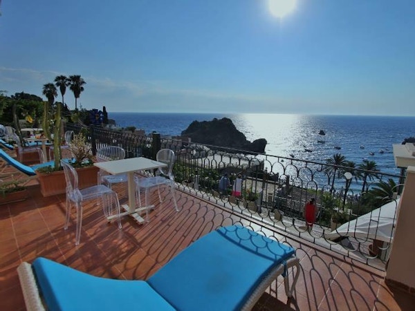 Blå solstoler på en terrasse over havet og stranden