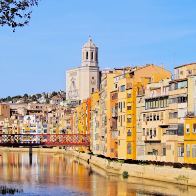 Fargerike hus i Girona som reflekterer i Onyar-elven.