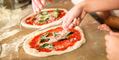 Forbereder klassisk pizza Margherita. Kokker tilsett revet parmesanost. Selektivt fokus