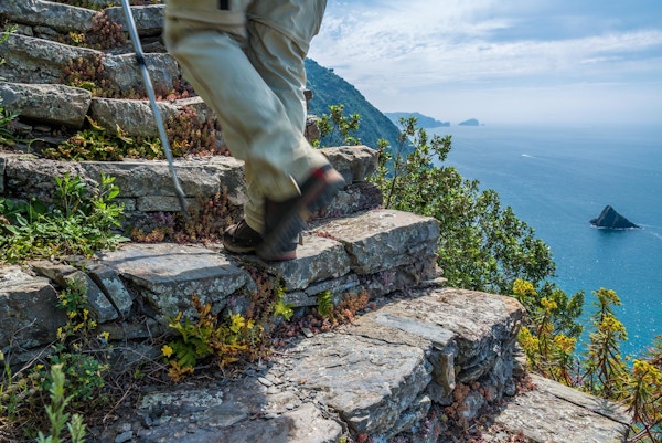 Steintrapp der en vandrer går oppover med utsikt over havet på ene siden