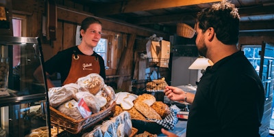 Bakervarer til salgs i gårdsbutikk med en kunde og en ekspeditør