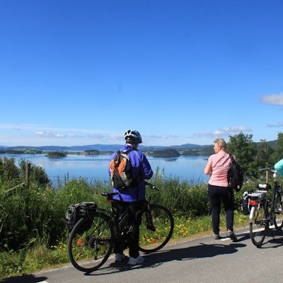 Syklister med sekk som tar en pause og ser utover fjorden