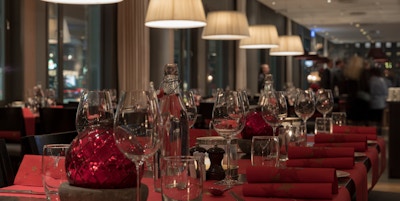 Bord dekket opp til fest og jul med rød bordpynt, tallerkner og glass