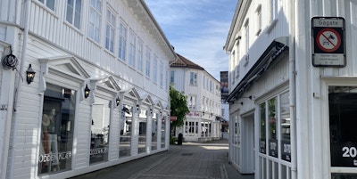 Smal gågate med toetasjes hvite hus langs veien, med butikker i første etasje