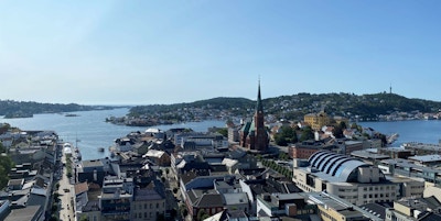 Oversiktbilde over byen Arendal sett ovenfra med bygninger, kirke, øyer og vann