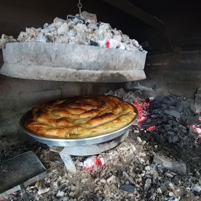 Det lages en ostepai inne i et ildsted med kull