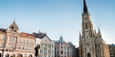 "Det sentrale torget i Novi Sad, Serbia eller Trg Slobode. Synlig er tradisjonell arkitektur, parochial romersk-katolske kirke med navnet Marias og statuen av Svetozar Miletic. Se flere bilder som dette i:"