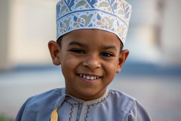 Liten Omani-gutt som smiler og koser seg i parken