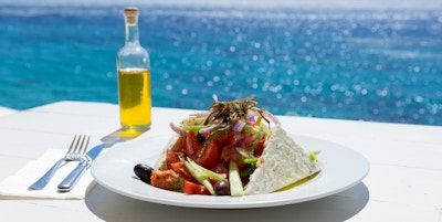 Gresk salat og olivenolje på solfylt havoppsett