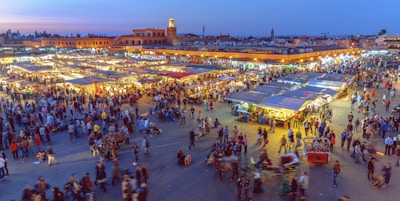 Den berømte Djemaa El Fna-plassen i tidlig kveldslys, Marrakech, Marokko med Koutoubia-moskeen i bakgrunnen.