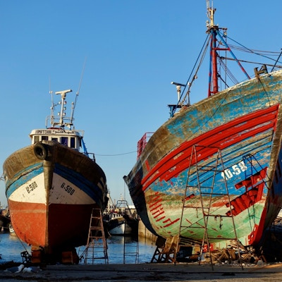 to fiskebåter i land ved en havn under reparasjon