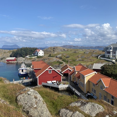 Gåsvær sett fra en høyde med sjøbua, tre hus og postbåten som ligger til kai