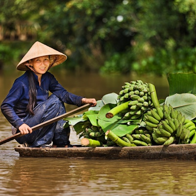 Vietnamesisk kvinne som ror en båt på Mekong elvedelta, Vietnam
