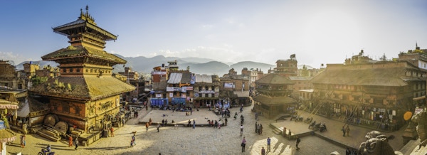 Varmt solnedgangslys som fyller de travle brosteinene på Taumadhi-plassen, oversett av de gamle templene i Bhaktapur, UNESCOs verdensarvliste i Kathmandu, Nepal.