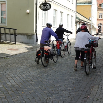 Fire syklister med hjelm triller syklene inne i liten by