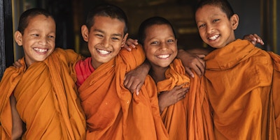 Gruppe av glade nybegynner-buddhistiske munker i dører i klosteret i Bhaktapur, Nepal. Bhaktapur er en gammel by i Kathmandu-dalen og er oppført som et verdensarvsted av UNESCO for sin rike kultur, templer og kunstverk av tre, metall og stein.